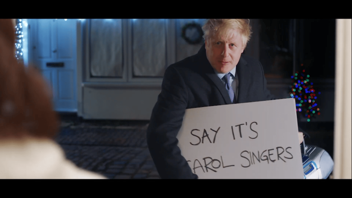 Boris Johnson holding a "Say it's carol singers" sign, recreating the Love Actually doorstep scene